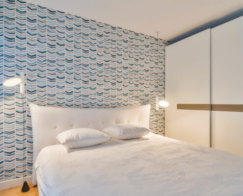 Chambre coté mer avec un papier peint dans les tons de bleus, une belle tête de lit accueillante , par Elisabeth Hamard, architecte d'intérieur