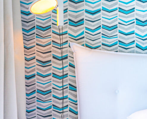 Détail du luminaire en tête de lit devant le papier peint bleu, architecte d'intérieur