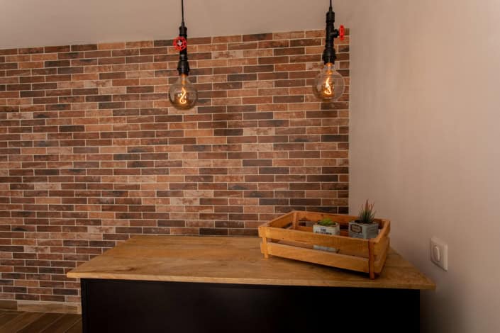 Détail du bar avec les suspensions au look industriel et le mur en briques à l'arrière, par Elisabeth Hamard, Architecte d'intérieur à Toulon • Var
